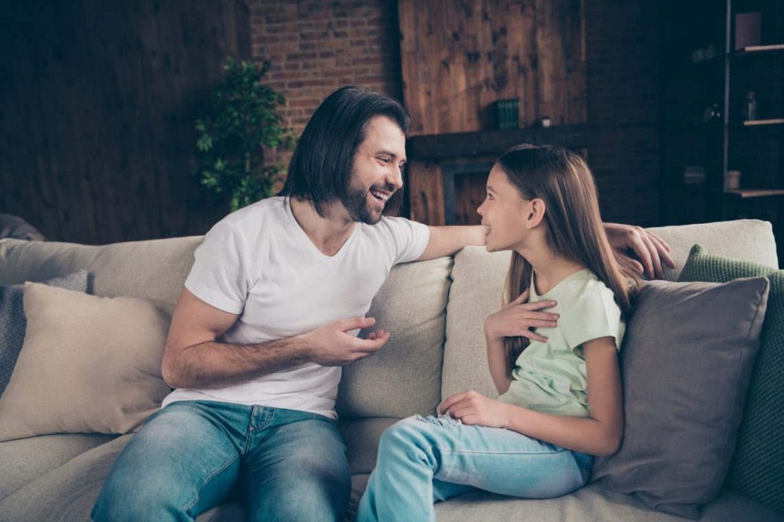 Un père âgé échange avec sa fille dans le salon après son retour de l’hôpital.