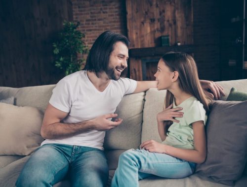Un père âgé échange avec sa fille dans le salon après son retour de l’hôpital.