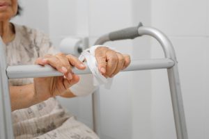 Personne âgée utilisant un déambulateur dans une salle de bain aménagée avec des équipements pratiques.