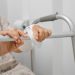 Personne âgée utilisant un déambulateur dans une salle de bain aménagée avec des équipements pratiques.