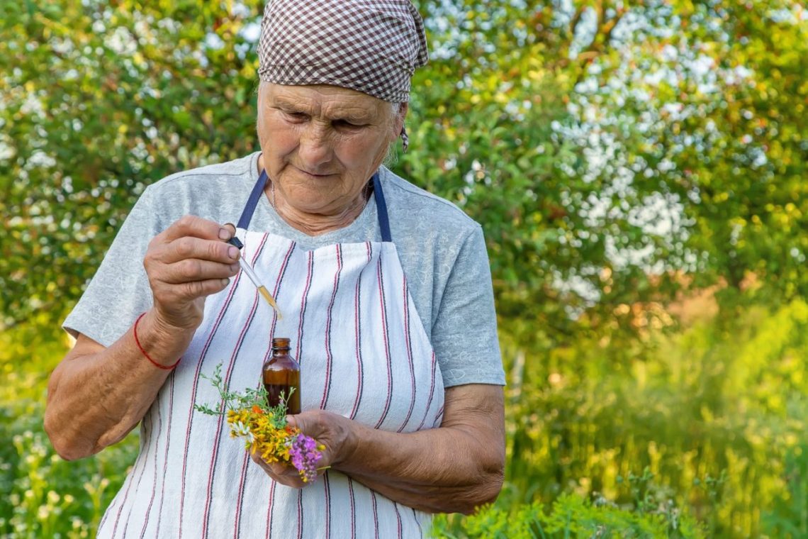 Une personne âgée vérifie ses médicaments et des compléments à base de plantes sur une table.