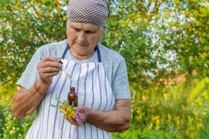 Une personne âgée vérifie ses médicaments et des compléments à base de plantes sur une table.