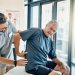 Un senior échange avec un ostéopathe au sujet d’une douleur lombaire, dans un cabinet de soins.