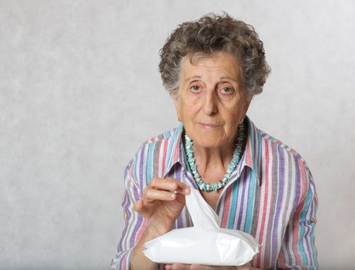 Femme âgée assise à table devant une assiette presque intacte après un veuvage.