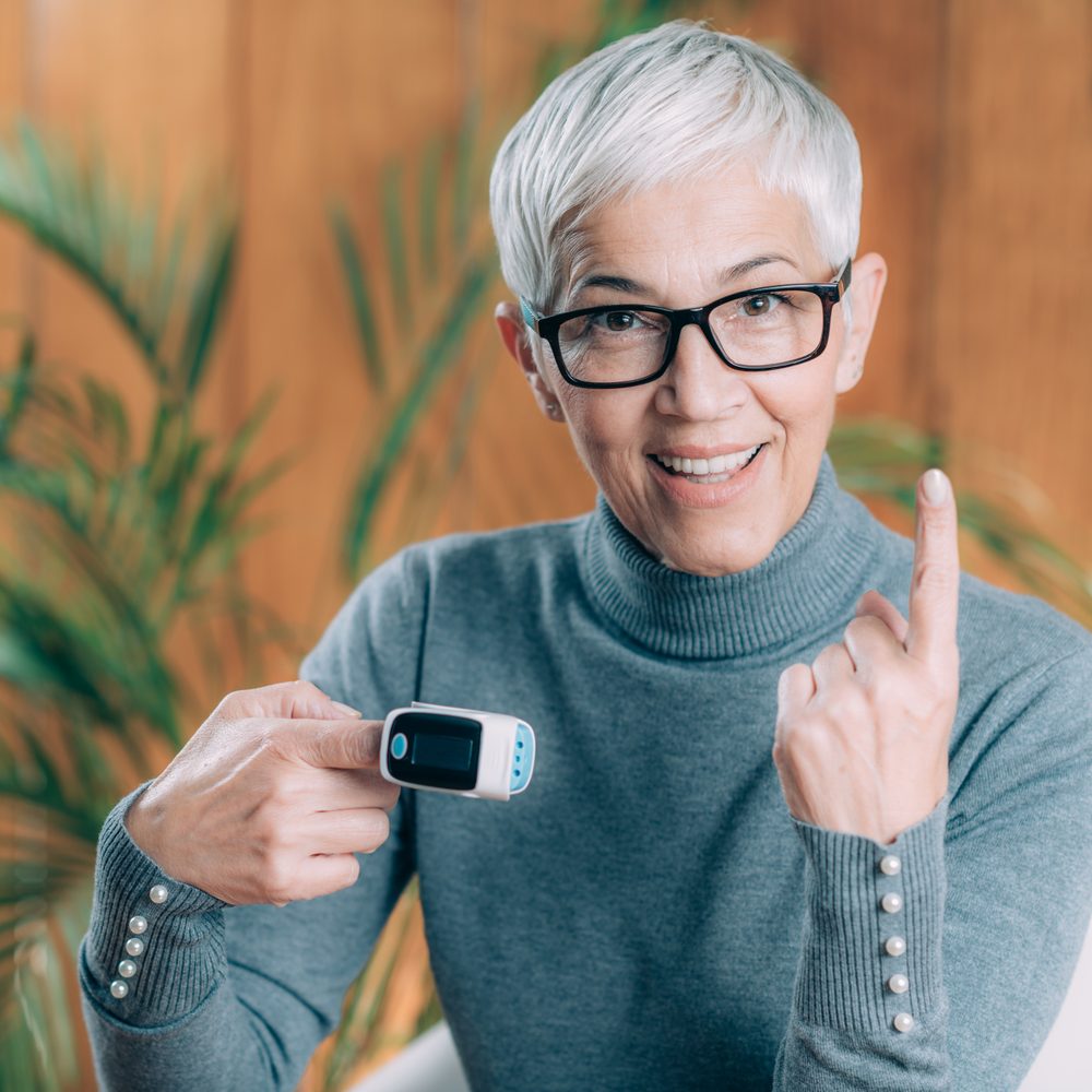 Senior utilisant un bouton d’alerte sans smartphone dans son salon.