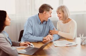 Un couple âgé examine des documents financiers avec un conseiller pour préparer sa protection future.
