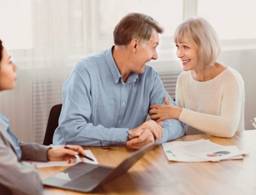 Un couple âgé examine des documents financiers avec un conseiller pour préparer sa protection future.