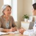 Une femme d'environ 55 ans échange calmement avec une médecin dans un cabinet médical lumineux et accueillant.