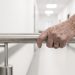 Une personne âgée marche prudemment dans un couloir dégagé équipé d’une rampe murale.